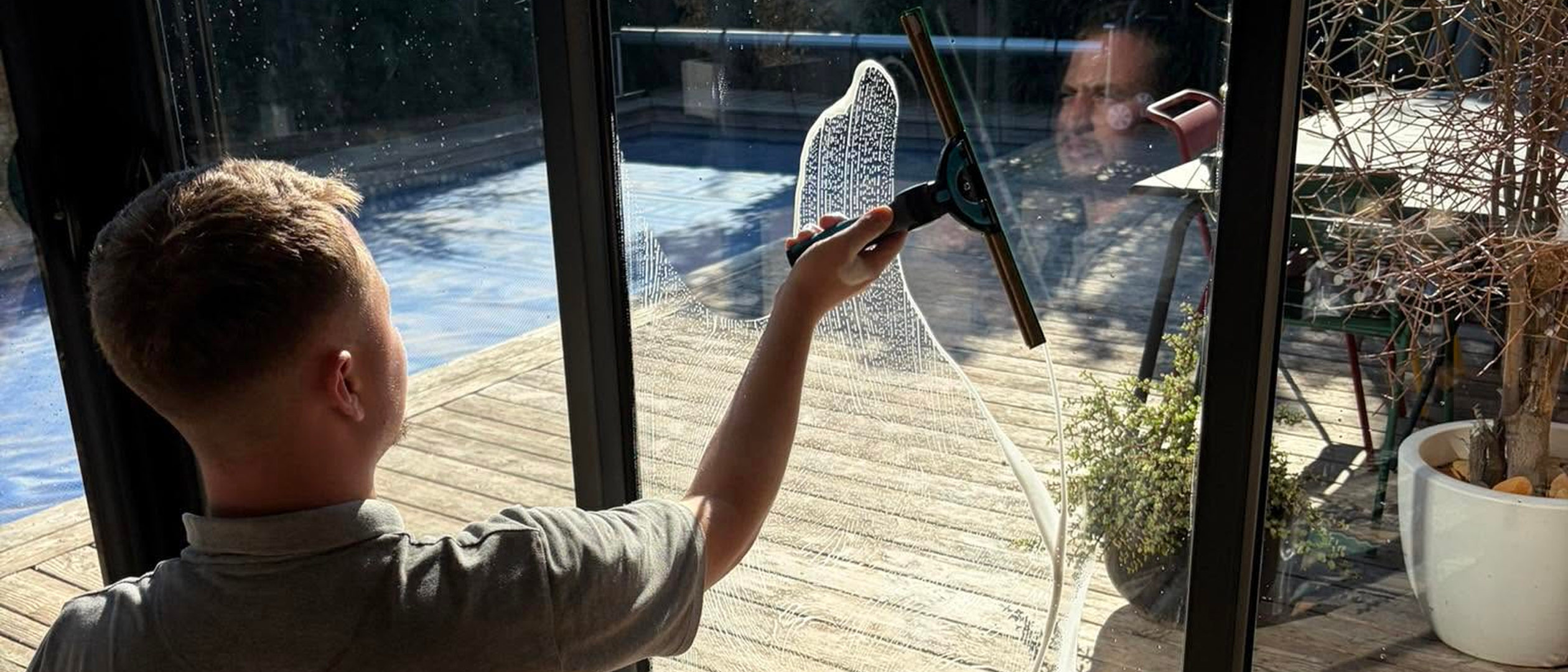 Thomas de ROVCLEAN nettoie une grande baie vitrée à la raclette